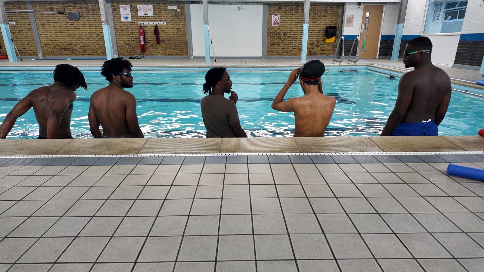 Adult Aqua Jetz students sitting at the pool edge before a lesson